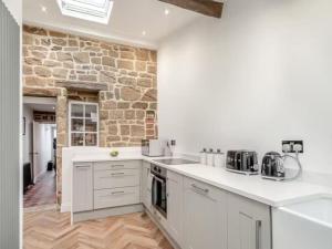 une cuisine avec des placards blancs et un mur en briques dans l'établissement Stoney Nook Cottage, à Guisborough