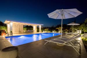 a swimming pool with two chairs and an umbrella at Antigone Estate in Koskinou