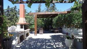 einen Garten mit einer Pergola, einem Tisch und Stühlen in der Unterkunft Antigone Estate in Koskinou