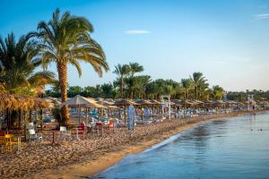 een strand met parasols en stoelen bij Fort Arabesque Resort, Spa & Villas in Hurghada