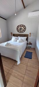 Schlafzimmer mit einem großen weißen Bett und Holzboden in der Unterkunft Casa temporada jaguaripe bahia toca do guaiamum in Jaguaripe