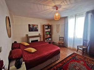 een slaapkamer met een groot rood bed en een open haard bij Maison au calme avec terrasse et jardin in Chinon
