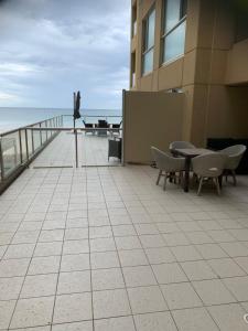 uma varanda com mesas e cadeiras e um pássaro num edifício em Pier 108 Glenelg em Glenelg