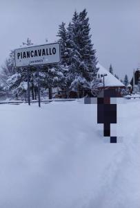 um sinal de rua na neve ao lado de uma árvore em CASA DESIRE' em Piancavallo