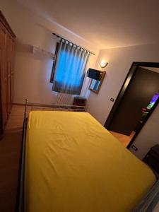 a yellow bed in a room with a window at CASA DESIRE' in Piancavallo