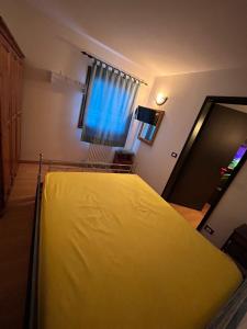 a yellow bed in a room with a window at CASA DESIRE' in Piancavallo +2 photos