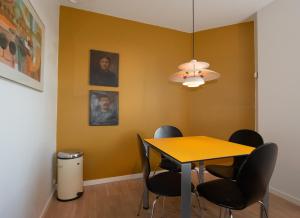 een eetkamer met een gele muur en een tafel en stoelen bij Guesthouse Tradsborgvej in Tjæreborg