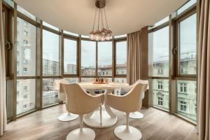 - une salle à manger avec une table, des chaises et de grandes fenêtres dans l'établissement Apartamenty MUNN 5 Szczecin - Golden, à Szczecin