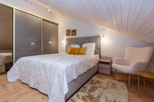 a bedroom with a large bed and a chair at Memel Townhouse apartamentai in Klaipėda