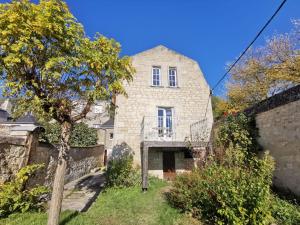 an old stone house with a tree in the yard at Maison au calme avec terrasse et jardin in Chinon