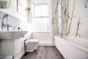 een witte badkamer met een wastafel, een toilet en een bad bij Apartment 4 - The Crescent in York +12 foto's