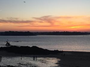 een groep mensen die bij zonsondergang op het strand staan bij Le Cosy Intra - Appt Cocon Parking privé in Saint-Malo