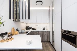 a kitchen with white cabinets and a white counter top at Flisac Apartment by LoftAffair in Warsaw