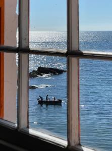 a window view of people in a boat in the water at Unique Retreat - 2 bedroom cliff top cottage with large terrace in Portloe