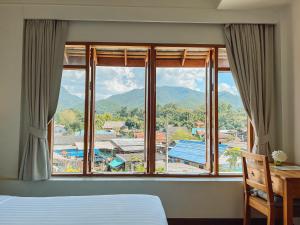 a bedroom with a large window with a mountain view at Pai Cherkaew Boutique House in Pai