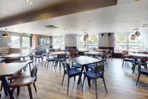 un comedor con mesas, sillas y ventanas en Village Hotel Hull en Hull