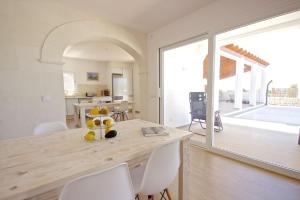 eine Küche und ein Esszimmer mit einem Holztisch und weißen Stühlen in der Unterkunft Villa Maravilla with HEATABLE pool ROOFTOPbar with sea views and Range Rover in Binibeca