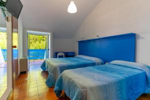 two beds in a room with a blue headboard at Corvino Resort in Monopoli +37 photos