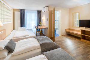 フライブルク・イム・ブライスガウにあるホテル クラシックのベッド2台とテレビが備わるホテルルームです。