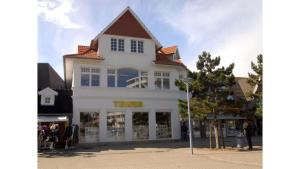 a white building with a taks store on a street at Wohnung Maren in Sankt Peter-Ording