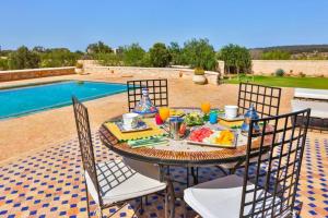 una mesa con un plato de comida junto a una piscina en Les Jardins De Mogador yoga et SPA, en Essaouira