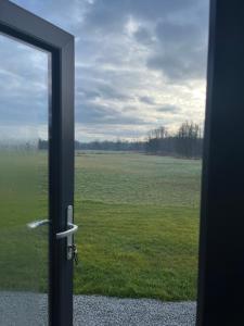 an open door with a view of a field at TinyHouse -Reset im Vilstal -Zurück zum Ursprung in Aldersbach