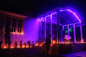 a group of people standing outside of a house with purple lights at The Inchara Hill View HomeStay in Chikmagalūr