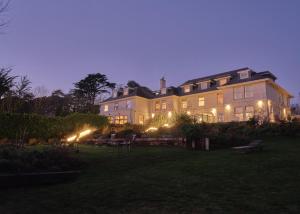韦德布里奇The St Enodoc Hotel的一座大房子,晚上在院子里放灯