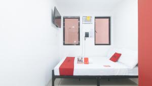 uma cama num quarto com um vermelho e branco em RedDoorz @ El Grande Inn Santa Cruz Manila em Manila