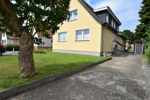 a yellow house with a tree in the driveway at Fewo In dat Huus in Grube