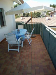 een tafel en stoelen en een parasol op een patio bij Comfy flat with balcony at 30metres from the beach in Lido