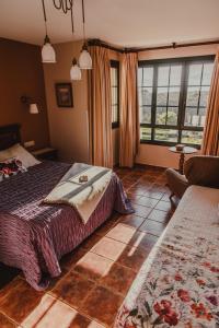 a bedroom with a bed and a couch and windows at Hotel Rural La Figar in Argüero