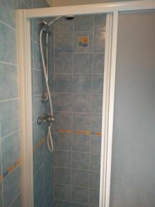 een douche in een badkamer met blauwe tegels bij Comfy flat with balcony at 30metres from the beach in Lido