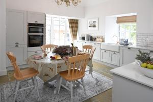 uma cozinha com mesa e cadeiras e uma cozinha com armários brancos em Stables Cottage em Perth