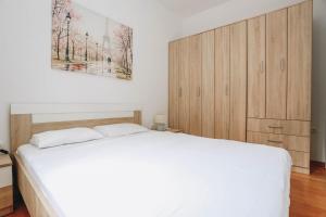 a bedroom with a white bed and wooden cabinets at Status-M Apartments Przno in Pržno