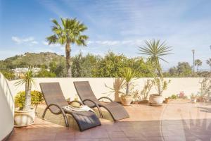 eine Gruppe von Stühlen auf einer Terrasse mit Palmen in der Unterkunft La Manga Club Resort - Los Olivos 43 in Atamaría