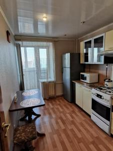 a small kitchen with a table and a refrigerator at 1 комнатная квартира в самом центре с видом на сквер in Kostanay