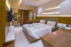 1 dormitorio con 1 cama grande y TV en Hotel Ravikiran, en Kolhapur