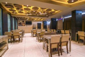 a restaurant with tables and chairs in a room at Hotel Ravikiran Kolhapur, NEAR GOKUL SHIRGAOV MIDC, KANERIWADI, 5 STAR MIDC, ON NH4 GOA HIGHWAY in Kolhapur