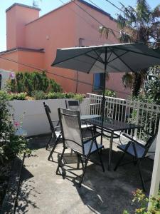 得利雅斯特的住宿－al porticciolo，一张桌子和两把椅子以及一把雨伞