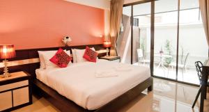 a bedroom with a large white bed with red walls at Ratana Residence Thalang in Thalang