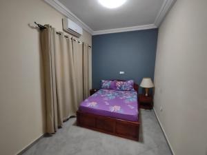 Cette petite chambre comprend un lit violet et des rideaux. dans l'établissement Villa N'KOMI, à Lomé