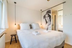 a bedroom with a large white bed with a mirror at Villa Paradis - De ultieme kustvilla met zwembad ! in Koksijde +99 photos
