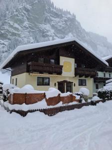 une maison recouverte de neige devant une montagne dans l'établissement Ferienwohnung Rohrmoser mit 2 Schlafzimmern, à Hüttschlag
