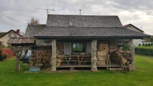 ein kleines Haus mit einem Haufen Feuerholz in der Unterkunft Dzika Chata in Nowy Barkoczyn