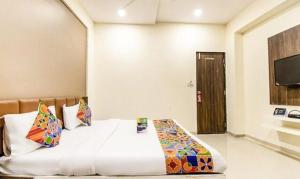 um quarto de hotel com uma cama com uma colcha branca em FabExpress Pratiksha em Ahmedabad