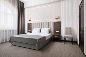 een slaapkamer met een groot bed en een stoel bij Mask Business Hotel in Pyatigorsk