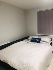 ein weißes Bett mit einem blauen Kissen darüber in der Unterkunft Cozy Flat in London! in London