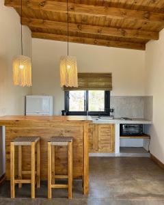 una cocina con una gran barra de madera con taburetes en Complejo Los Olivos - casa 3 y 4 en Cafayate