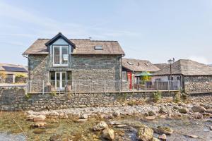 a stone house on the shore of a river at Forge Bridge Cottage Coniston in Coniston